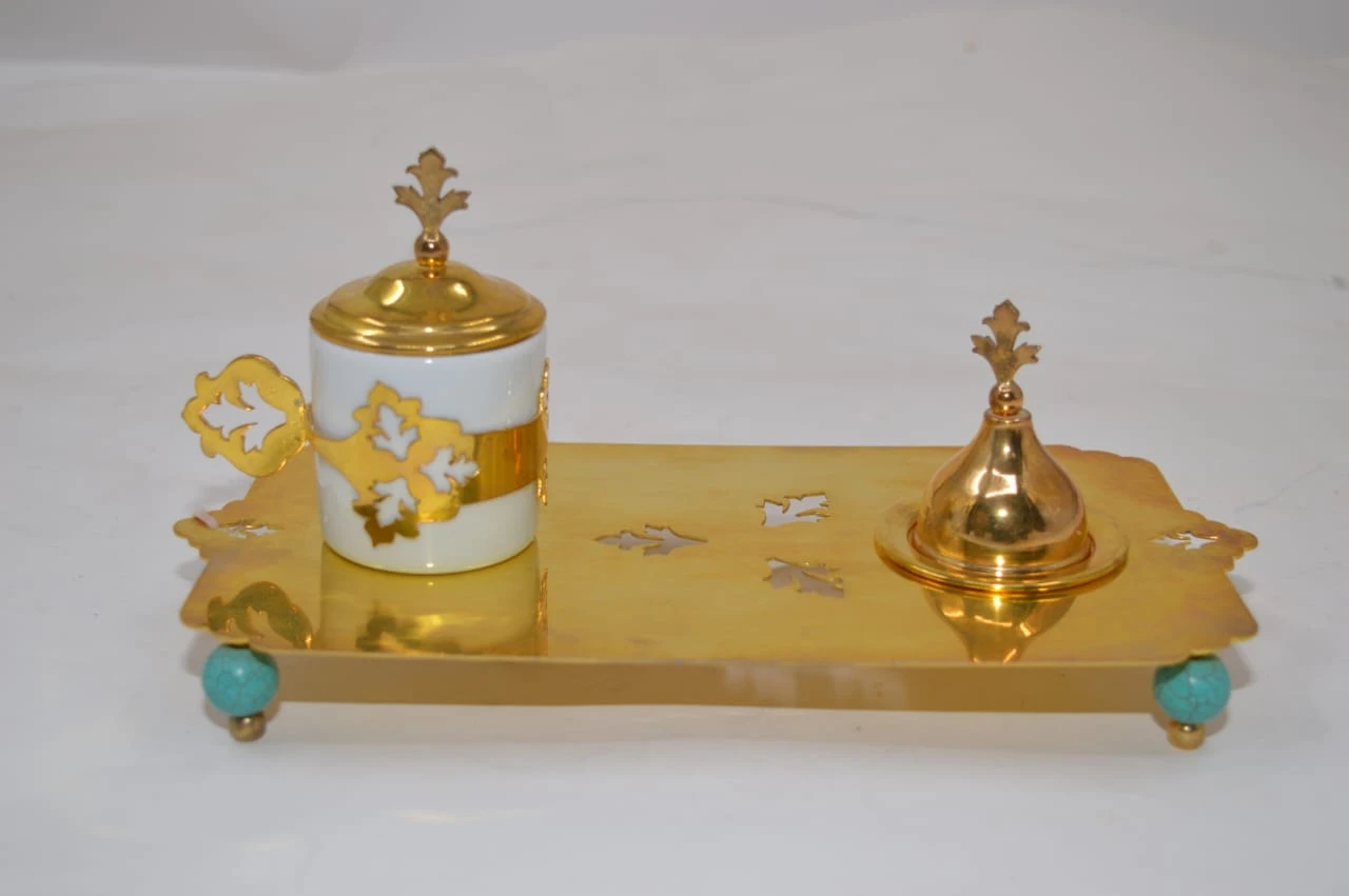 كوب قهوة مطلي بالذهب مع طبق حلوى